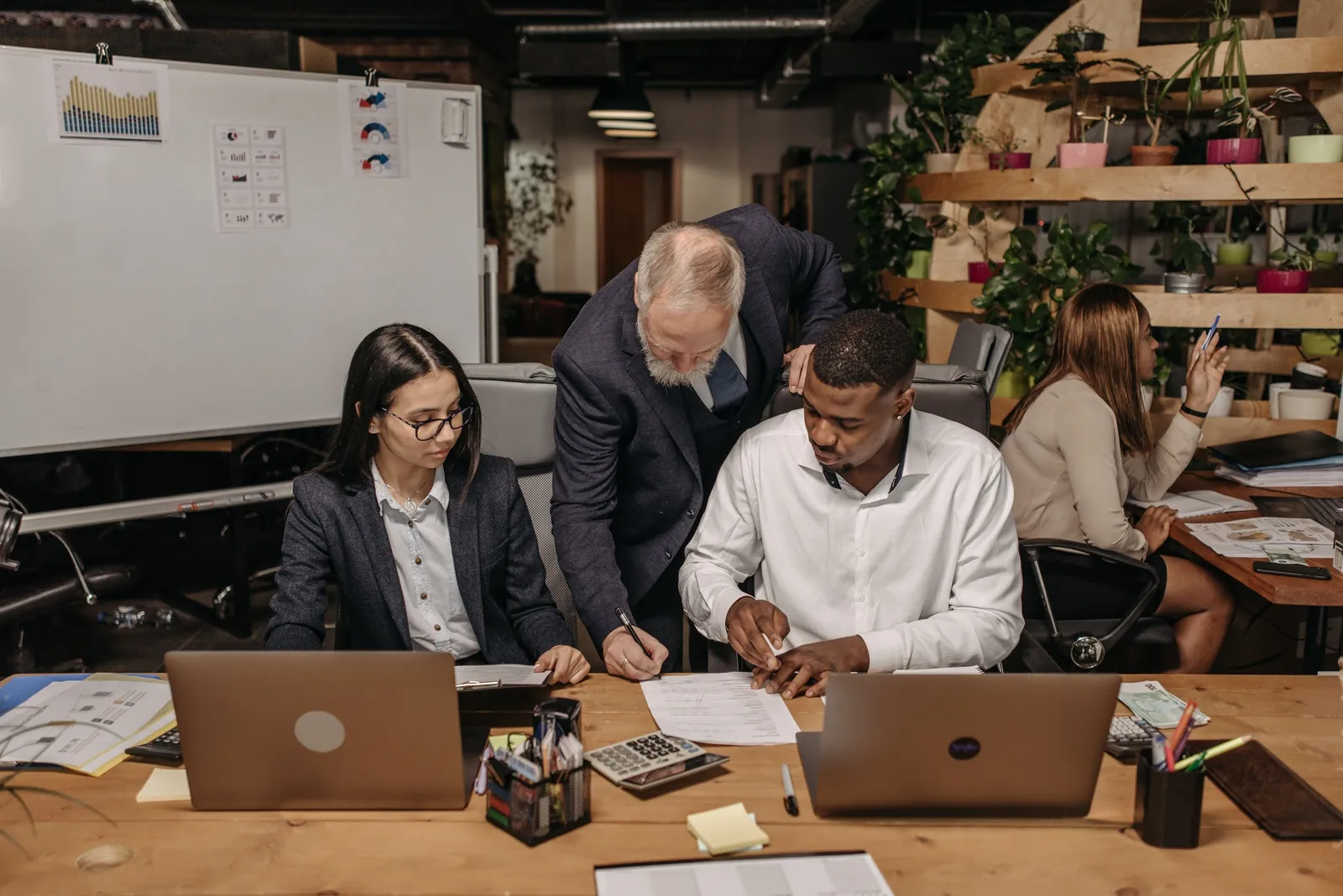 People gathered around a table with laptops and papers, working through a plan together.